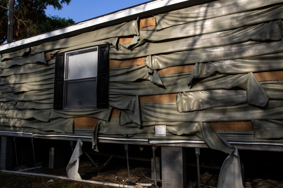 The outer walls of a neighboring trailer are warped and melted by the heat after the fire at...