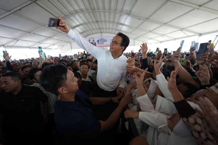 Anies Baswedan takes a photo with supporters during a campaign rally last week