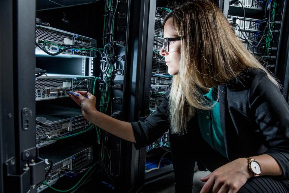 An engineer checking wires and switches for an enterprise data center server tower.