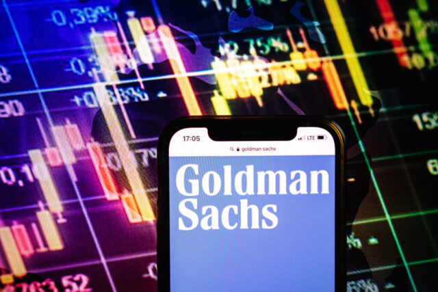 Smartphone displaying logo of Goldman Sachs company on stock exchange chart background