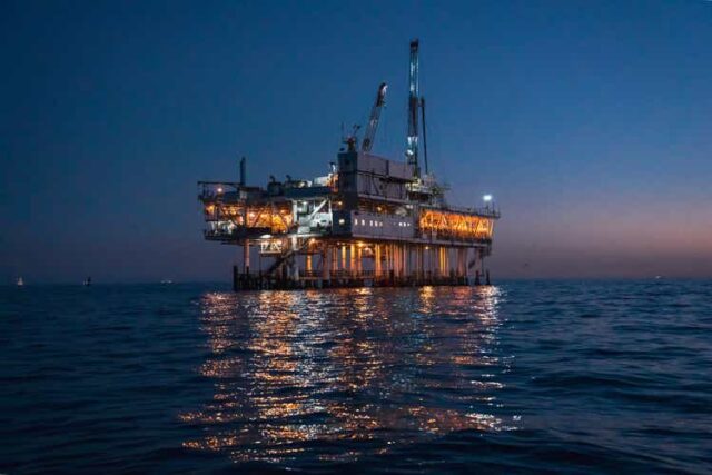 Night Time Offshore Oil Rig Drilling and Fracking Operation, Brightly Lit, on Calm Seas