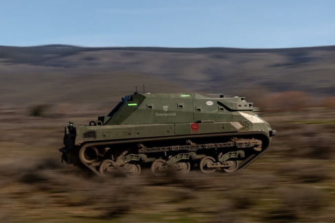 Image from the side of a tank driving fast through off-road terrain
